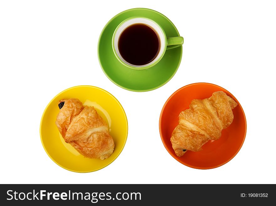 There are two cups with tea on the white background, orange and green. Also there are sweets on the saucer