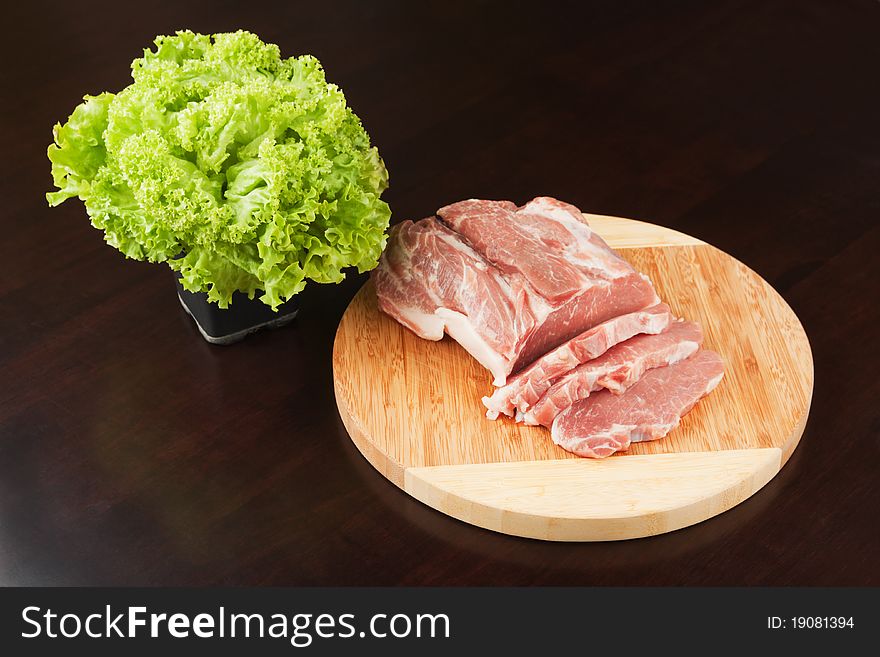Meat on a cutting board and the bandle of the lettuce. Meat on a cutting board and the bandle of the lettuce.