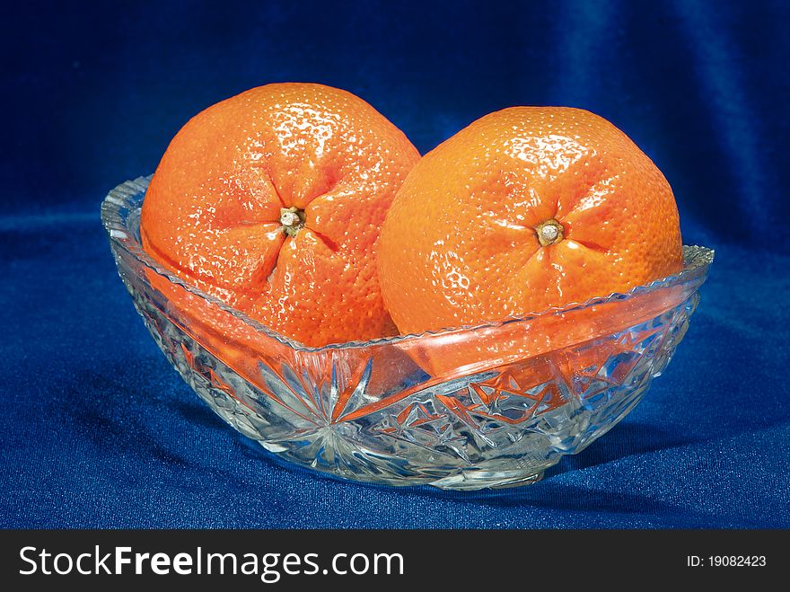 Two tangerines in a glass vase on a dark blue background. Two tangerines in a glass vase on a dark blue background