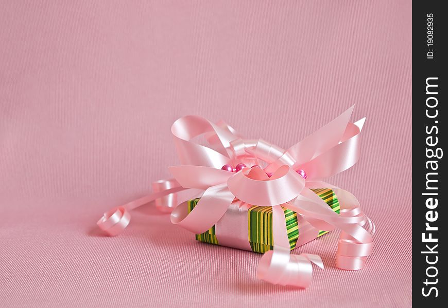 Green gift box with pink ribbon and bow on the pink background. Green gift box with pink ribbon and bow on the pink background.