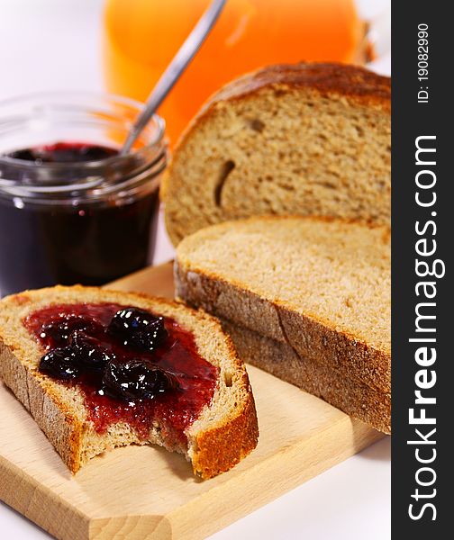 Slices of bread with cherry jam and orange juice in the background