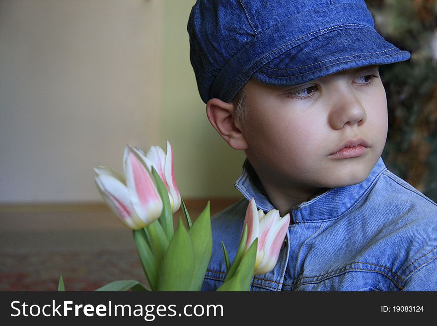 Blue boy with blue cap and blue jacket with sharp look. Boy with three tulips in hands. Blue boy with blue cap and blue jacket with sharp look. Boy with three tulips in hands.