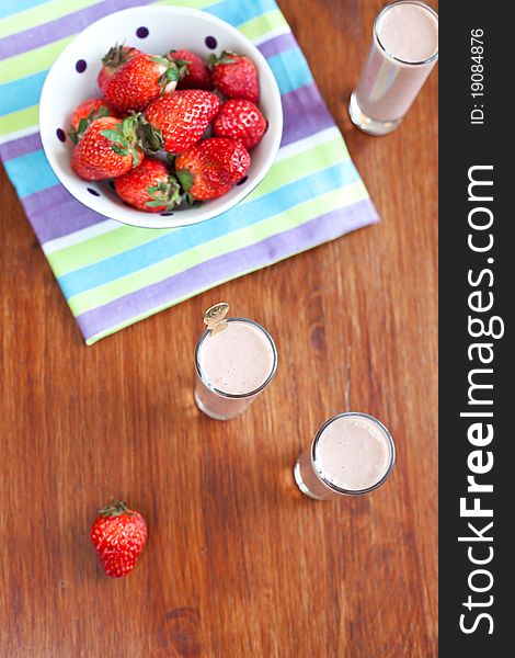 Yogurt cocktail on the wooden table with bowl of strawberries. Yogurt cocktail on the wooden table with bowl of strawberries