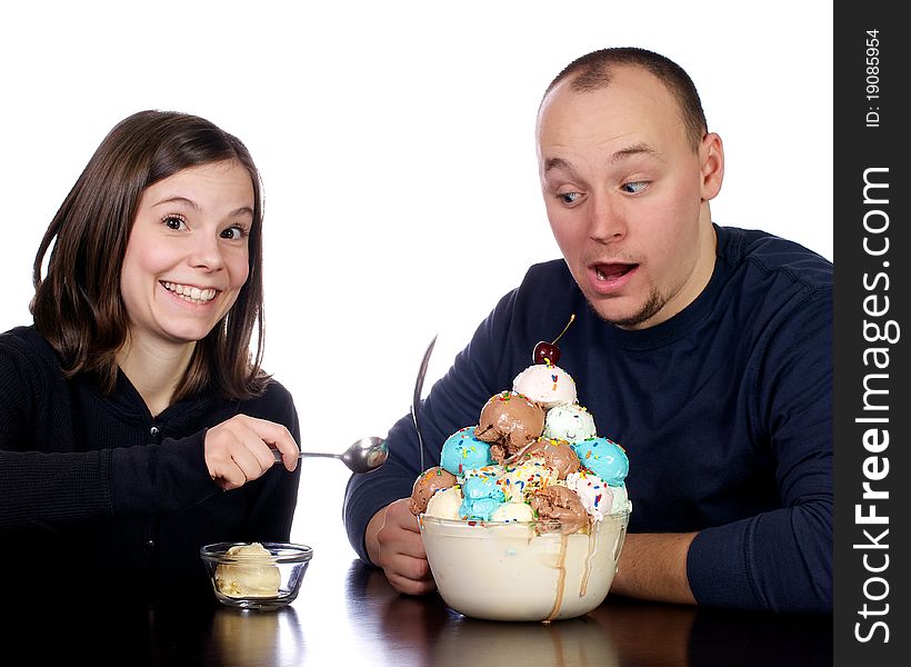 Young man cautiously watches his wife try to steal a spoon full of his giant bowl of multi-flavored scoops of ice cream. Young man cautiously watches his wife try to steal a spoon full of his giant bowl of multi-flavored scoops of ice cream.