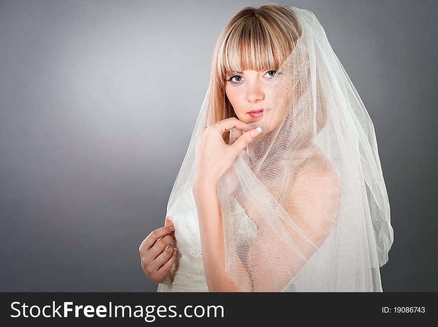 Closeup portrait of a bride under the veil in studio neutral background