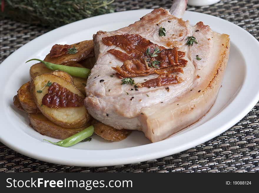 Pork chop with crispy bacon, pan-fried potatoes and green beans