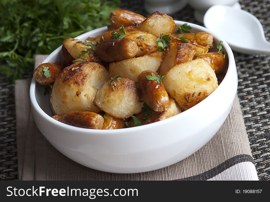 Cocktail sausages with roast potatoes and herbs in a bowl