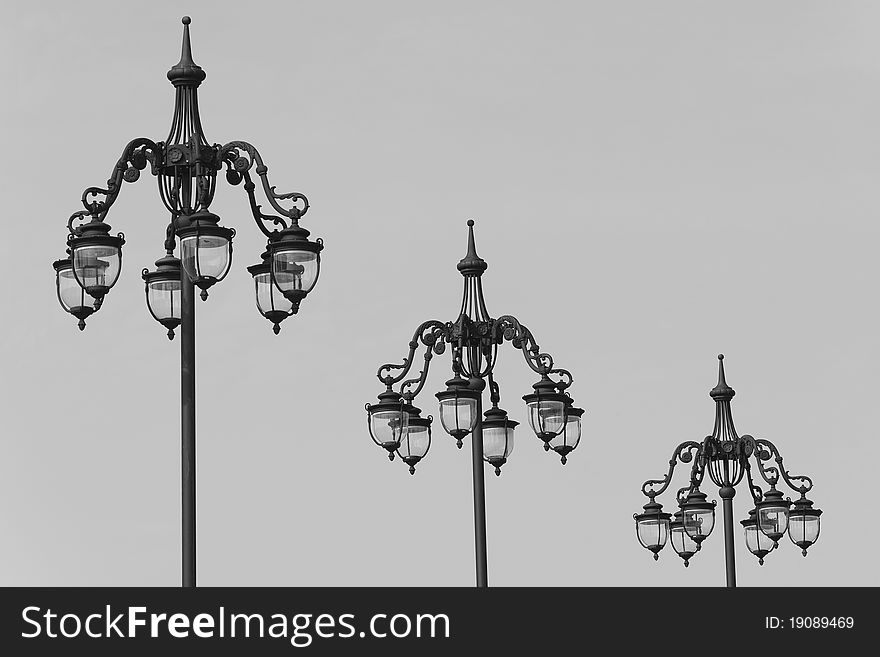 Three vintage lamp posts on light gray sky. Three vintage lamp posts on light gray sky