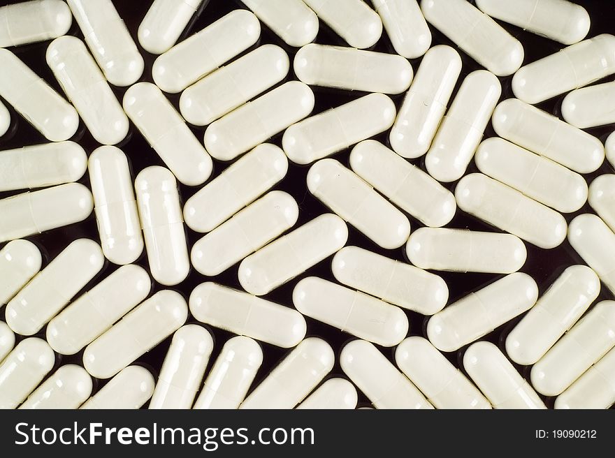 White pills (capsules) on black background