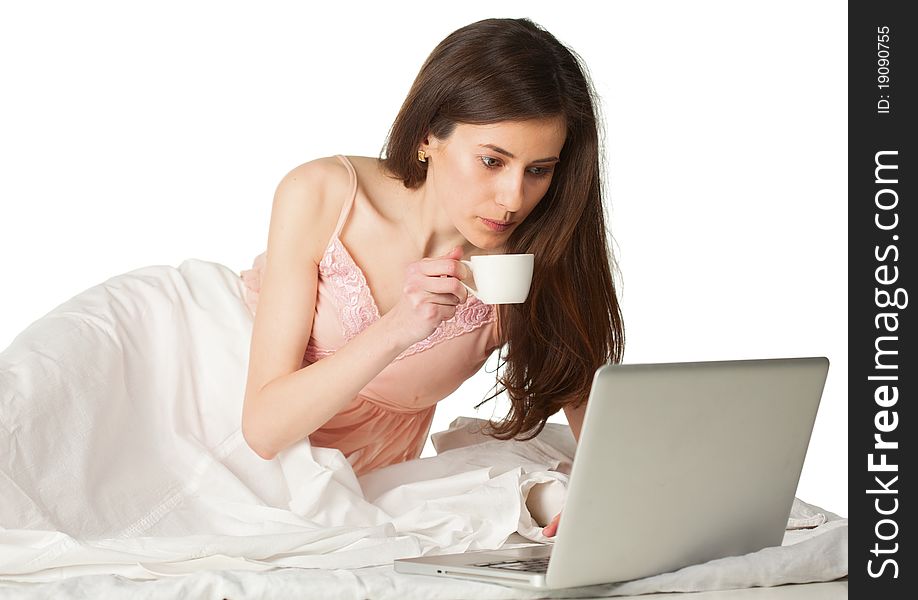 The girl with cup of coffee and silver laptop in the bad on a white background. The girl with cup of coffee and silver laptop in the bad on a white background