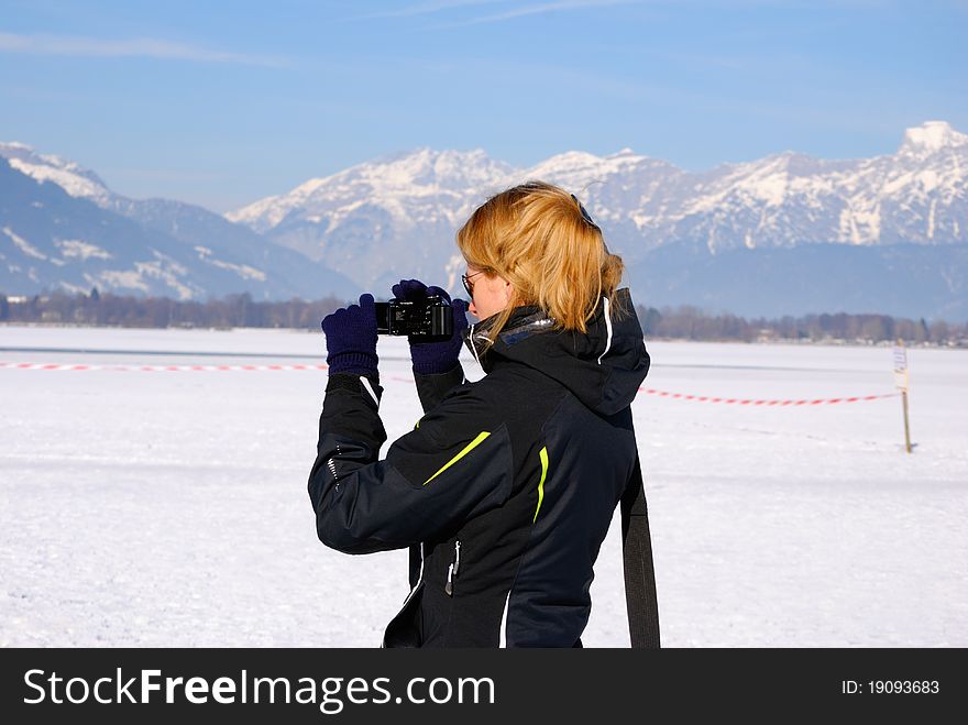 Woman with camcorder filming panorama of austrian winter.