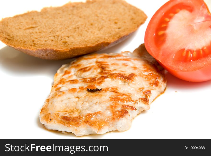 Fried piece of meal with bread and tomato over white. Fried piece of meal with bread and tomato over white