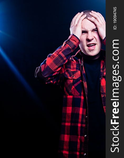 Young man is desperate because of stage lights and fame. He has red opened shirt with black t shirt under that. He is on black isolated background. Young man is desperate because of stage lights and fame. He has red opened shirt with black t shirt under that. He is on black isolated background.