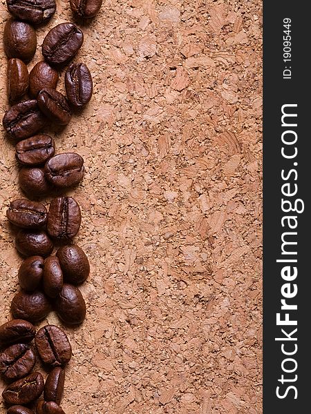 A pile of coffee beans forming a simple stripe frame on a natural corkwood background. A pile of coffee beans forming a simple stripe frame on a natural corkwood background