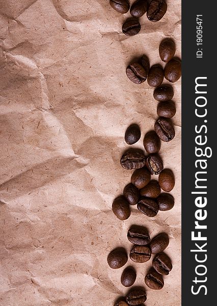 A pile of coffee beans forming a simple stripe frame on a crumpled paper background. A pile of coffee beans forming a simple stripe frame on a crumpled paper background