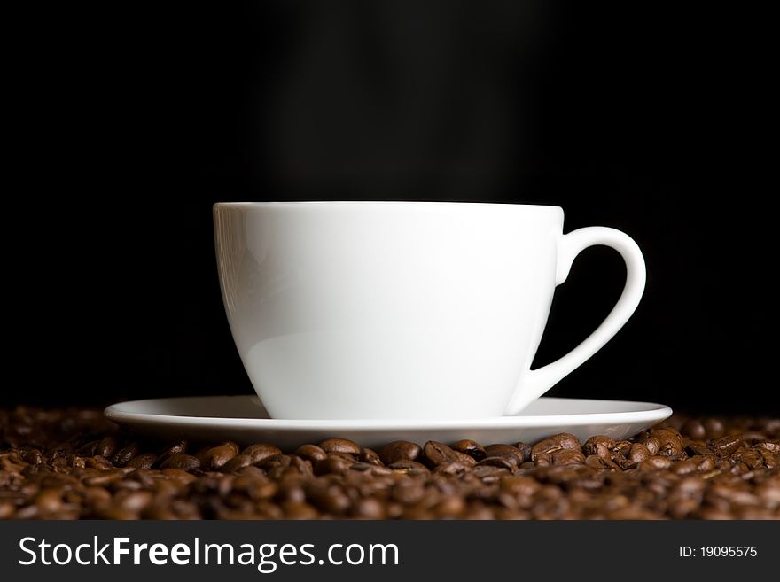 White cup with hot coffee and steam on dark background