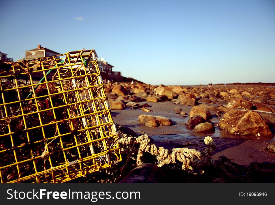 Lobster pot lying on a rock-filled beach at sunset. Lobster pot lying on a rock-filled beach at sunset