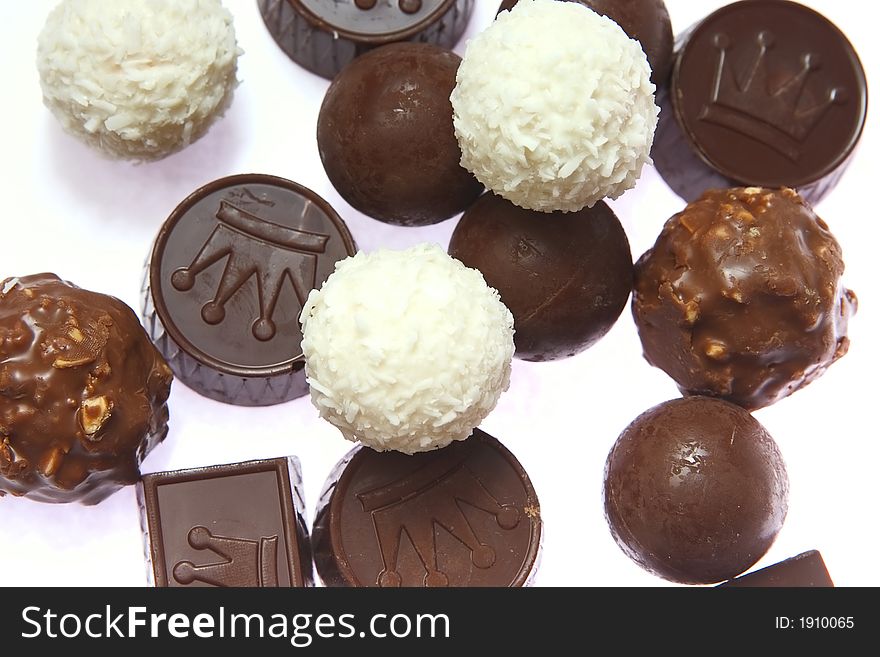 Appetizing chocolate candies with a nut and coconut are sparse on a white background