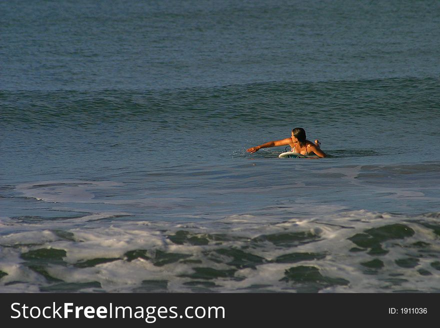 Woman Paddling to Catch a Wave While Surfing