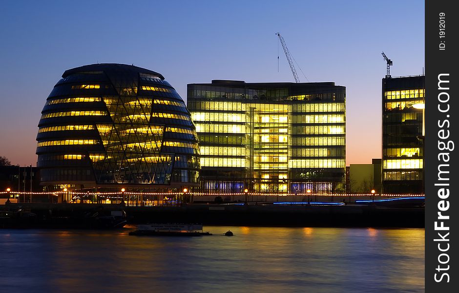 Office buildings on the bank of Thames River at nighttime.