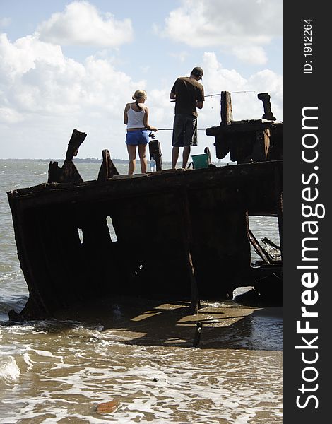 Young couple are fishing on an old ship wreck. Young couple are fishing on an old ship wreck