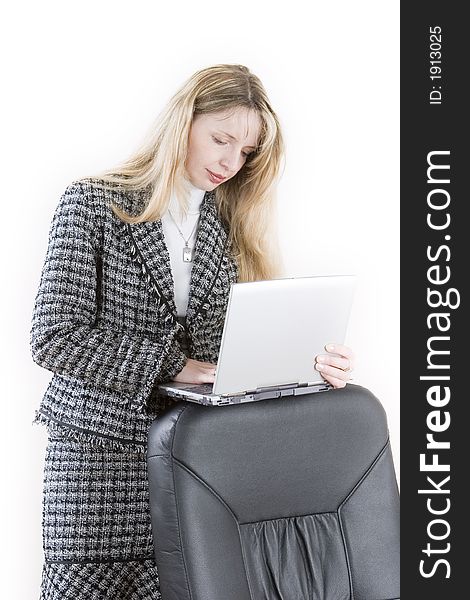 A woman resting a laptop on the back of a chair. A woman resting a laptop on the back of a chair