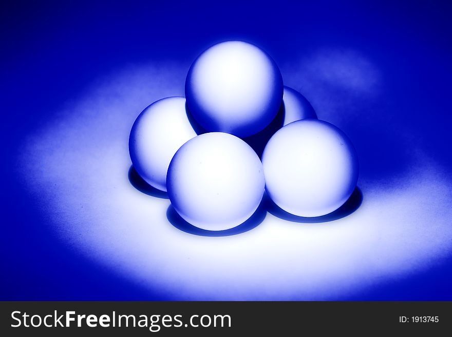 Four white balls for table tennis built a pyramid and illuminated from beneath blue light