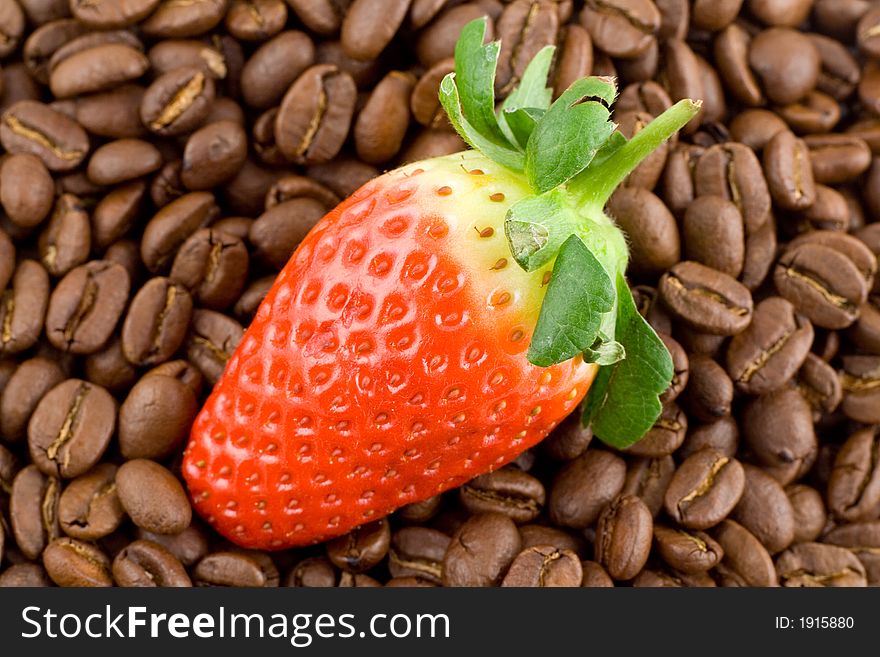 Coffee beans, close-up, blured, colombian coffee bean with bright red strawberry on top of them. Coffee beans, close-up, blured, colombian coffee bean with bright red strawberry on top of them