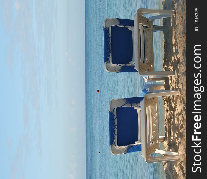 Two blue and white beach chairs facing the ocean