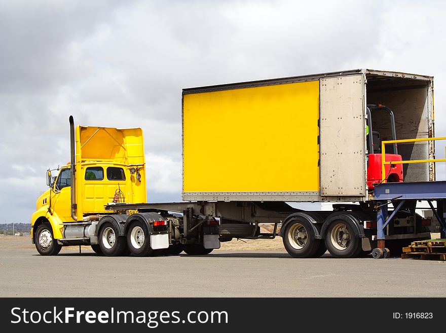 Semi truck on loading dock with forklift