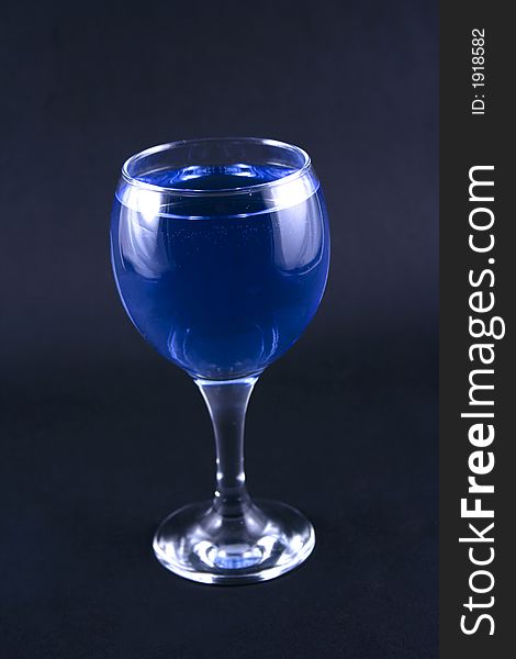 Glass with a blue drink on a black background
