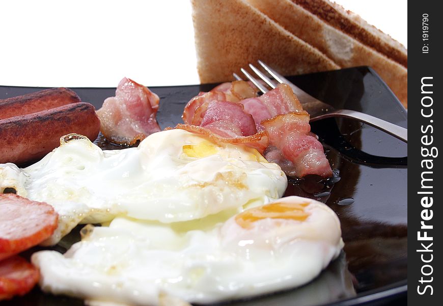 Platter of scrambled eggs with bacon sausages and toast bread