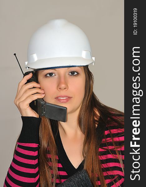 A girl in a white construction helmet, said by mobile phone with a customer. A girl in a white construction helmet, said by mobile phone with a customer