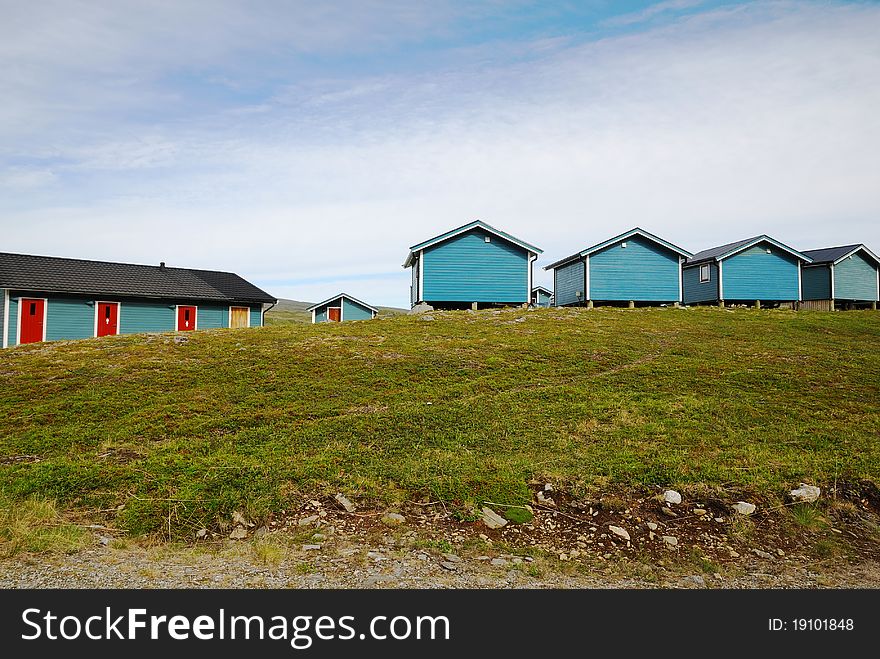 Several row of wooden houses are located on the green moss hill. Mageroya is photographed in summer. Several row of wooden houses are located on the green moss hill. Mageroya is photographed in summer.