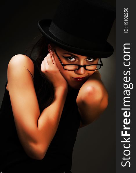 The young woman in a black dress and glasses posing in studio. The young woman in a black dress and glasses posing in studio