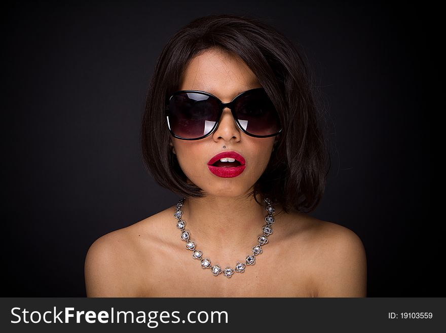 Sexy brunette elegant woman expressed wearing neckles  and sunglasses