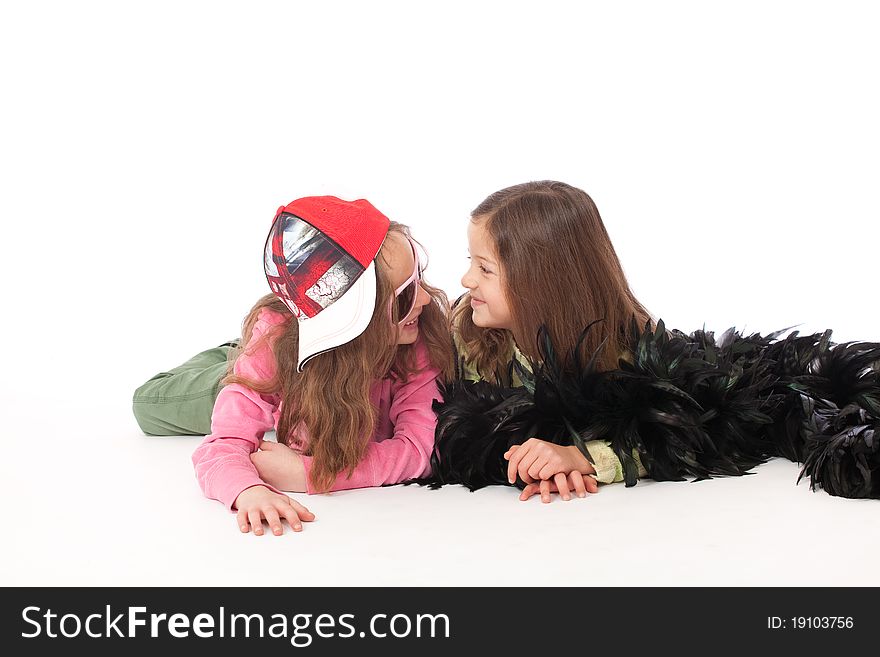 Two freinds looking and smiling and lying isolated with cap and feather boa