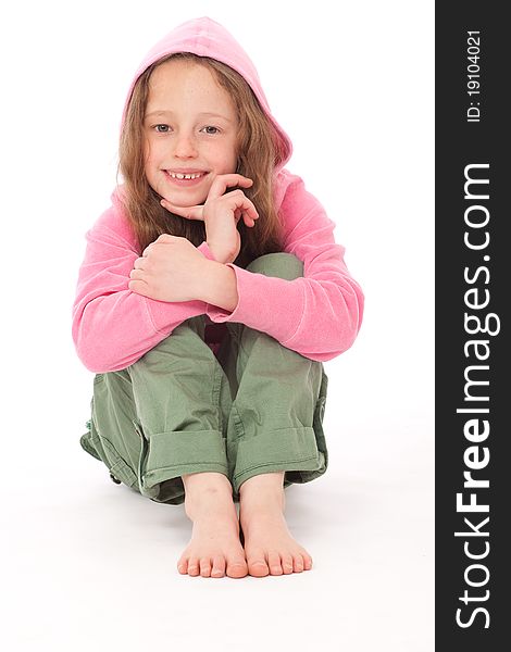 Young girl in pink hood top and green trousers sitting on floor and smiling. Young girl in pink hood top and green trousers sitting on floor and smiling