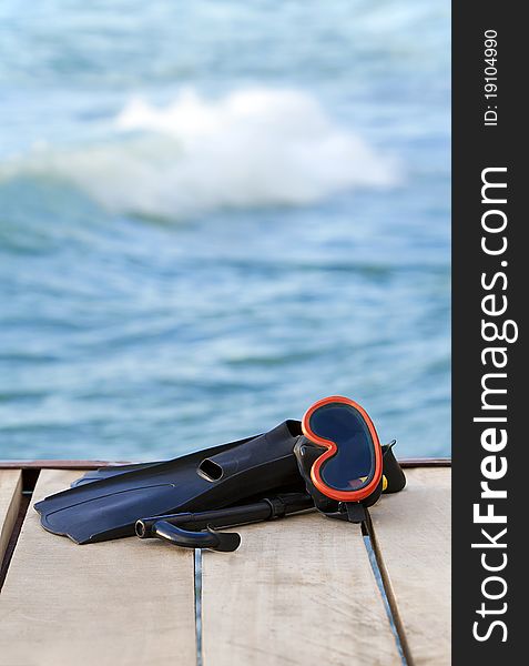 A view of diving goggles, swimming fins and snorkel near the lake. A view of diving goggles, swimming fins and snorkel near the lake