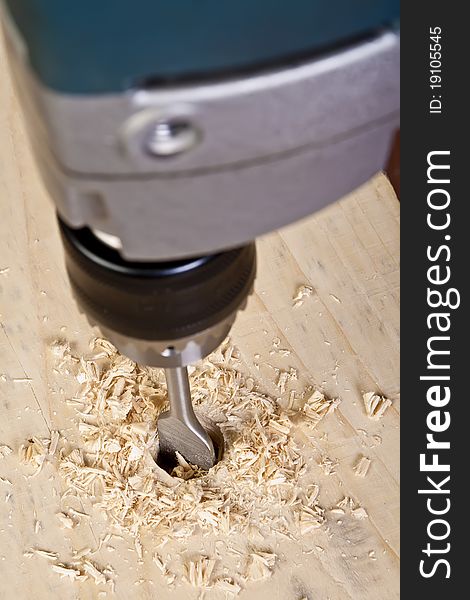 A man drilling a hole in wooden block