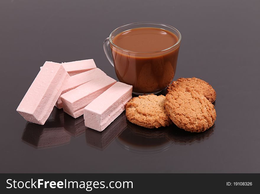 Coffee with milk and wafers against a dark background with reflexion