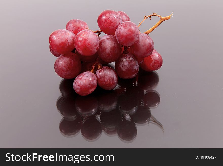 Cluster of red large grapes against a dark background with reflexion