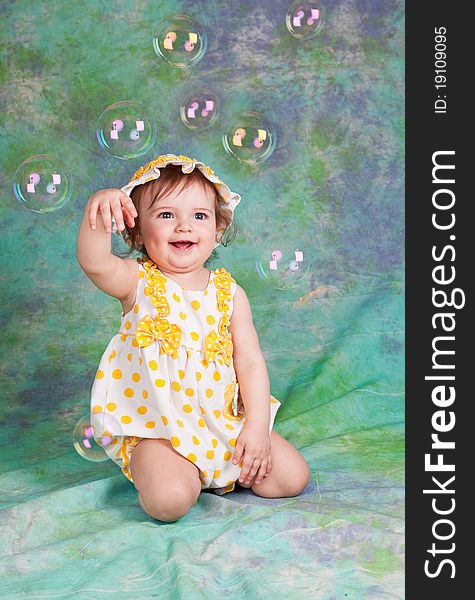 Portrait of the laughing child with soap bubbles on a green background in studio. Portrait of the laughing child with soap bubbles on a green background in studio