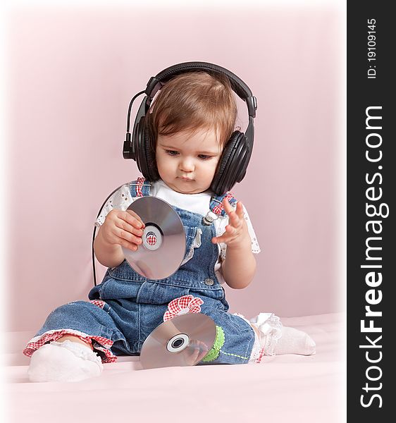 Child with CD discs sits and listens to music in earphones. Child with CD discs sits and listens to music in earphones