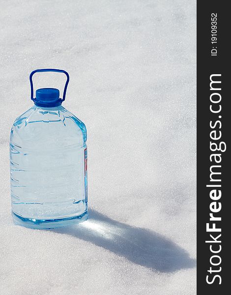Bottle with pure transparent water on snow in a bright sunlight. Bottle with pure transparent water on snow in a bright sunlight