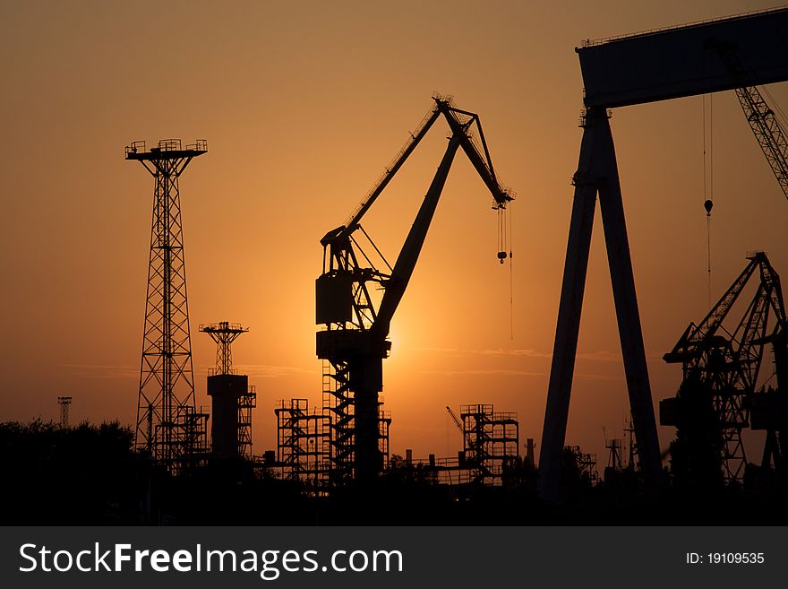 Dark silhouettes of tower cranes against sunset. Dark silhouettes of tower cranes against sunset.