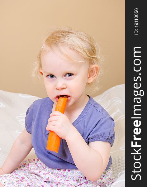 Cute girl eating carrot at home. Cute girl eating carrot at home