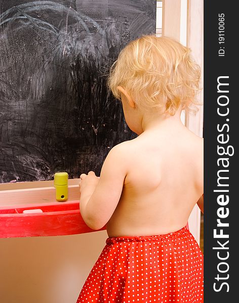 Baby girl drawing on chalkboard