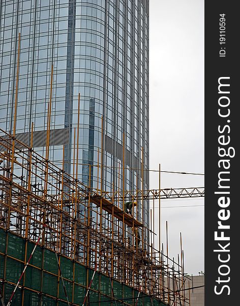 A builder working on the scaffold for another skyscraper. A builder working on the scaffold for another skyscraper