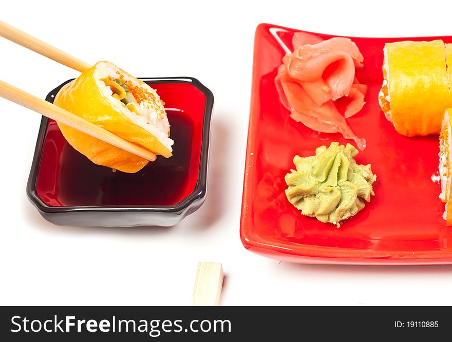 Yellow sushi rolls served on a plate. White background